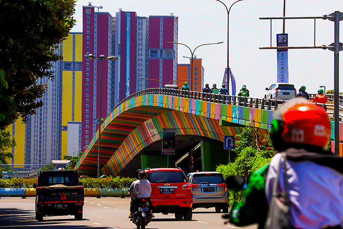 Pengendara melintas berlatar belakang gedung RSDC Wisma Atlet Kemayoran, Jakarta Pusat, Kamis (14/4/2022).