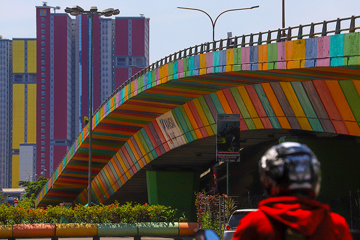 Pengendara melintas berlatar belakang gedung RSDC Wisma Atlet Kemayoran, Jakarta Pusat, Kamis (14/4/2022).
