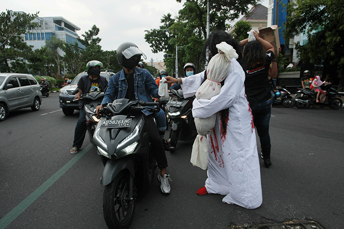 Aksi sekumpulan orang berkostum hantu yang tergabung dalam komunitas Semarangker membagi-bagikan takjil kepada pengguna jalan.