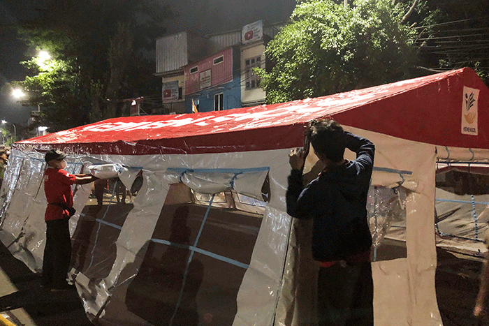 Petugas pemadam kebakaran bersama petugas Palang Merah Indonesia mendirikan tenda darurat untuk warga yang menjadi korban kebakaran di kawasan Pasar Gembrong.