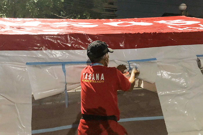 Petugas pemadam kebakaran bersama petugas Palang Merah Indonesia mendirikan tenda darurat untuk warga yang menjadi korban kebakaran di kawasan Pasar Gembrong.