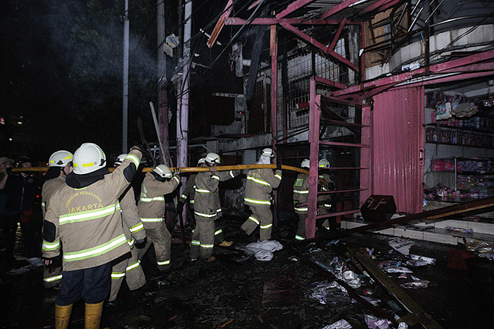 Petugas pemadam kebakaran berusaha memadamkan kobaran api yang membakar kios dan rumah warga di kawasan Pasar Gembrong, Jatinegara, Jakarta Timur.