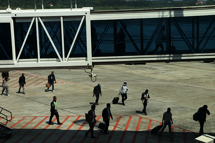 Sejumlah penumpang turun dari pesawat berjalan menuju terminal kedatangan di Bandara Internasional Jenderal Ahmad Yani, Kota Semarang, Jawa Tengah.