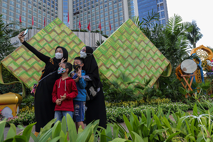 Warga berswafoto dengan latar belakang ornamen bernuansa lebaran yang terpasang di kawasan Bundaran HI, Jakarta Pusat, Selasa (26/4/2022).