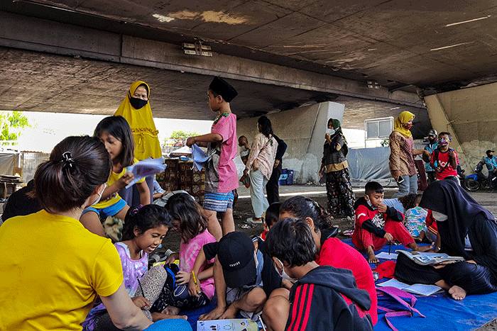 Anak-anak jalanan mengisi waktu berbuka dan belajar dibantu para relawan pengajar di kolong flyover Tomang, Jakarta Barat, Senin, (25/4/2022).