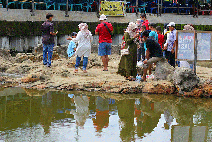 Pengunjung berfoto diatas batu yang dikisahkan sebagai Malin Kundang, di Pantai Air Manis, di Kota Padang, Kecamatan Padang Selatan, Sumatera Barat.