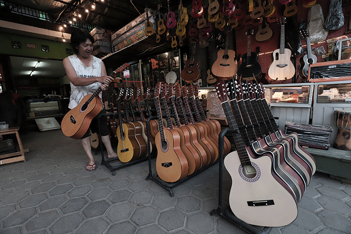 Penjual mencoba gitar di toko Eagle Music di kawasan Setu, Jakarta Timur, Sabtu (14/5/2022).