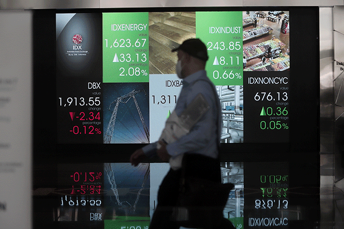 Petugas melintasi layar Pergerakan Indeks Harga Saham Gabungan (IHSG), BEI, Selasa (17/5/2022).