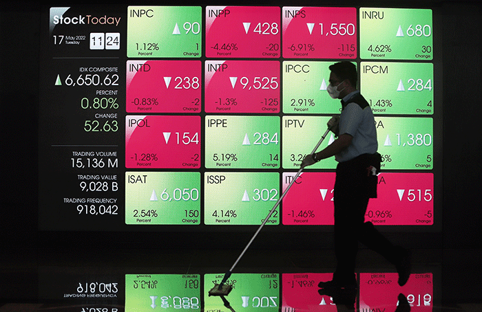 Petugas melintasi layar Pergerakan Indeks Harga Saham Gabungan (IHSG), BEI, Selasa (17/5/2022).