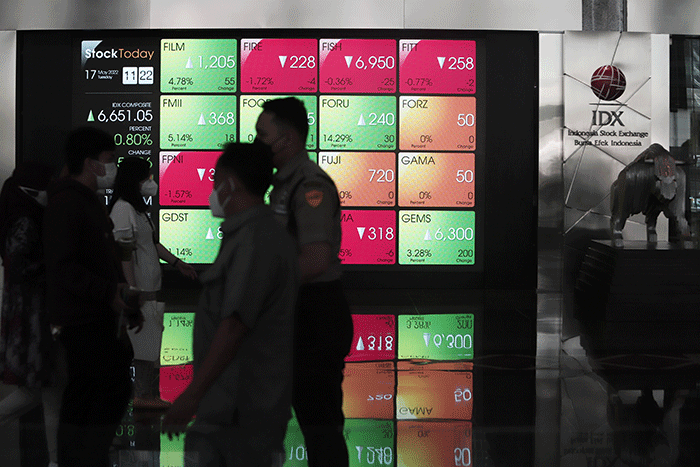 Pengunjung melintas di layar Pergerakan Indeks Harga Saham Gabungan (IHSG), BEI, Selasa (17/5/2022).