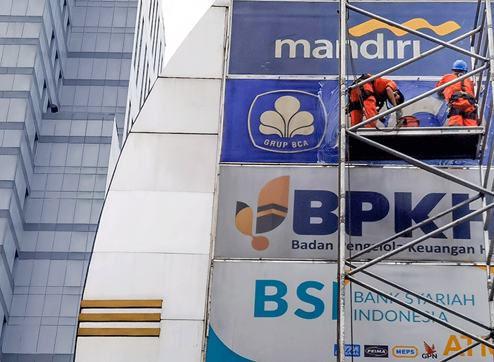 Pekerja membersihkan papan reklame di Gedung Perkantoran, Jakarta, Minggu (22/5/2022).