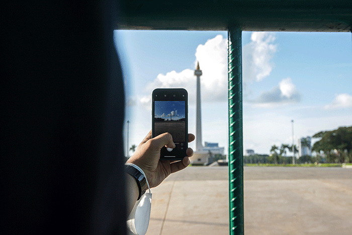 Sejumlah warga berfoto berlatar belakang Monumen Nasional (Monas) di Jakarta Pusat, Senin (23/5/2022).