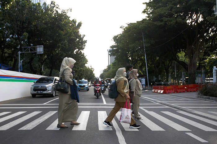 Sejumlah pekerja menyeberang jalan saat jam pulang kerja di kawasan Jalan Merdeka Selatan, Jakarta Pusat, Selasa (24/5/2022).