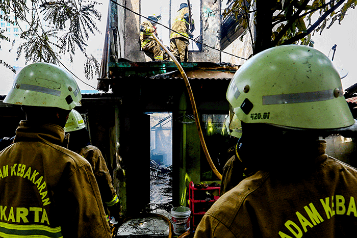 Petugas pemadam kebakaran berusaha memadamkan api yang membakar rumah warga di Jalan Masjid Alhuda atau depan Stasiun Kebayoran Lama.