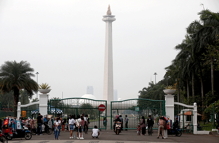 Warga berfoto dengan latar belakang Monumen Nasional di Jakarta, Kamis (26/5/2022).