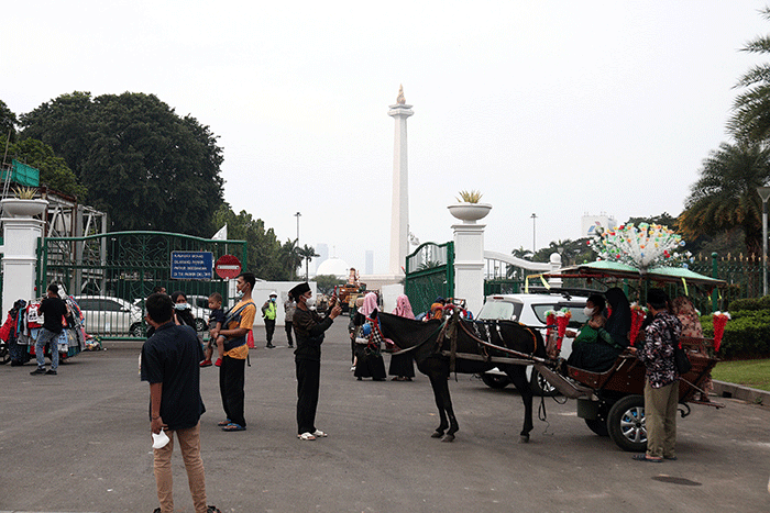 Warga berfoto dengan latar belakang Monumen Nasional di Jakarta, Kamis (26/5/2022).