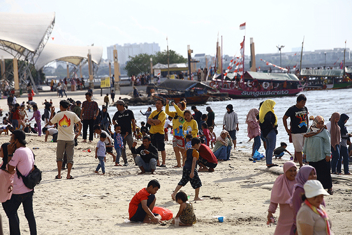 Warga berlibur di Pantai Ancol, Jakarta Utara, Rabu (1/6/2022).