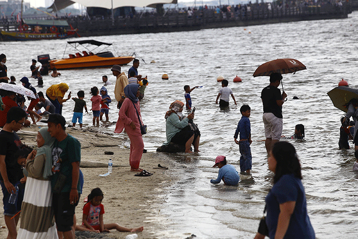 Warga berlibur di Pantai Ancol, Jakarta Utara, Rabu (1/6/2022).