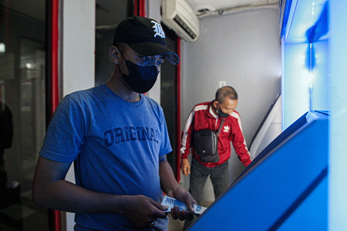 Seorang warga menunjukkan uang sebelum melakukan setor tunai di salah satu Anjungan Tunai Mandiri (ATM) kawasan Jakarta Timur, Kamis, (9/6/2022).