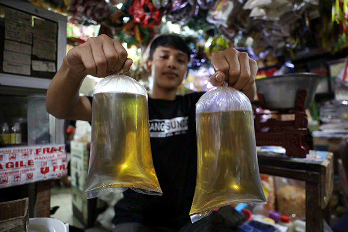 Pedagang menunjukkan minyak goreng curah di Pasar Kebayoran Lama, Jakarta, Senin (13/6/2022).