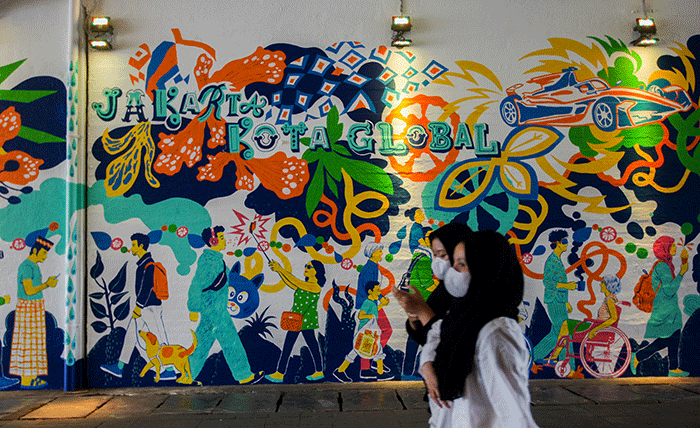 Sejumlah warga berjalan melintasi mural di Terowongan Kendal, Sudirman, Jakarta, Rabu (29/6/2022).