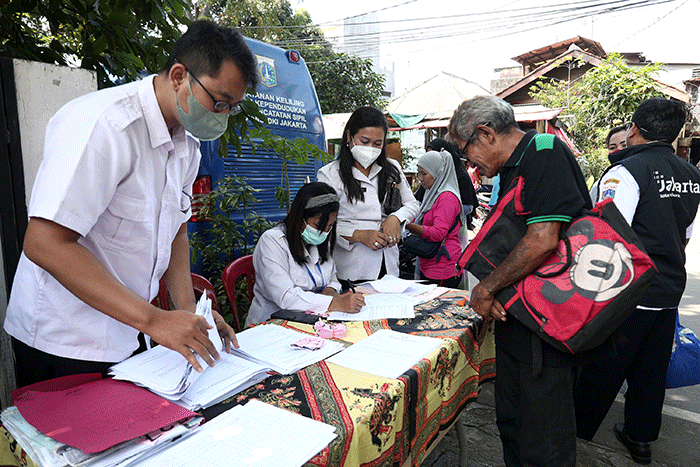 Petugas pelayanan keliling Dinas Kependudukan dan Pencatatan Sipil Provinsi DKI Jakarta membantu warga untuk mengurus data.