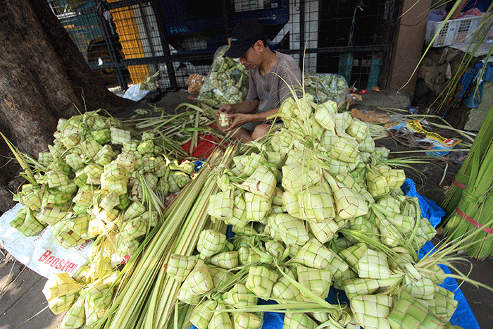 Pedagang membuat kulit ketupat untuk dijual di Pasar Palmerah, Jakarta, Sabtu (9/7/2022).
