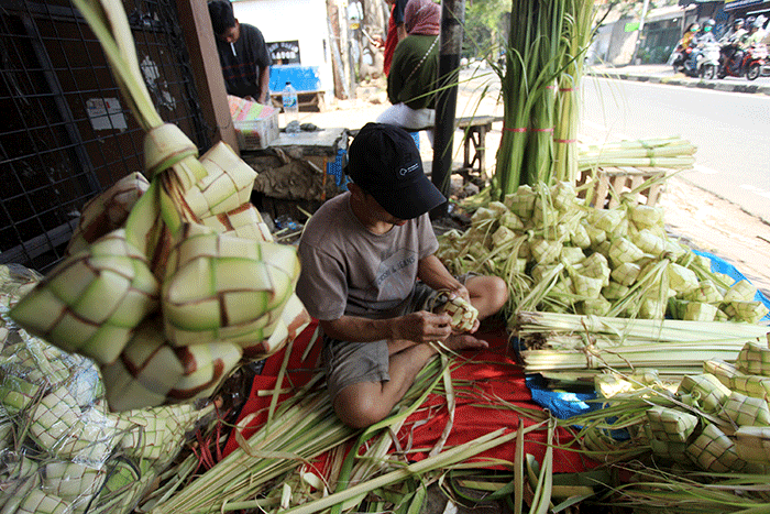 Pedagang membuat kulit ketupat untuk dijual di Pasar Palmerah, Jakarta, Sabtu (9/7/2022).