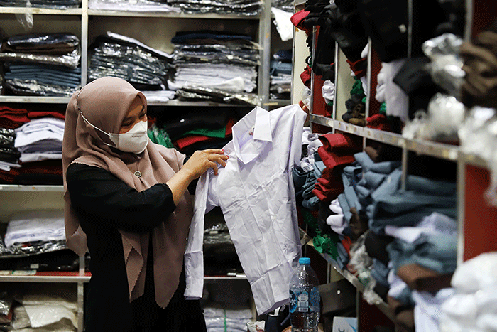 Orang tua memilih seragam sekolah baru untuk anaknya di salah satu kios di Pasar Kebayoran Lama, Jakarta, Sabtu (9/7/2022).