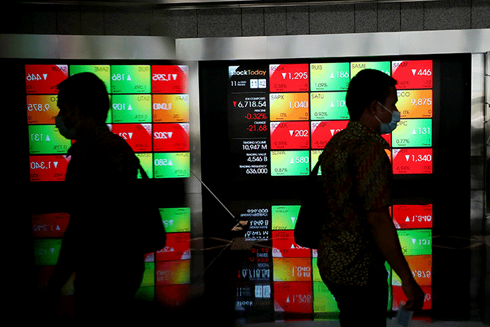 Karyawan melintas di depan layar pergerakan indeks harga saham gabungan (IHSG) di Bursa Efek Indonesia (BEI), Jakarta, Senin (11/7/2022).