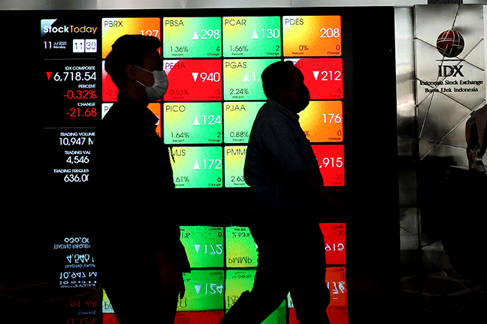 Karyawan melintas di depan layar pergerakan indeks harga saham gabungan (IHSG) di Bursa Efek Indonesia (BEI), Jakarta, Senin (11/7/2022).