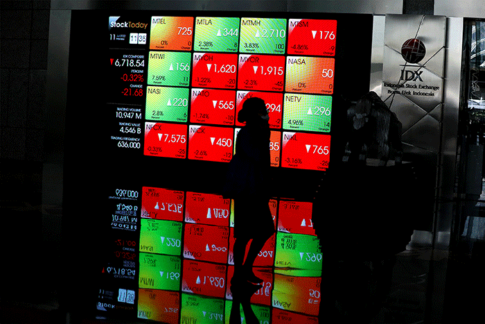 Karyawan melintas di depan layar pergerakan indeks harga saham gabungan (IHSG) di Bursa Efek Indonesia (BEI), Jakarta, Senin (11/7/2022).