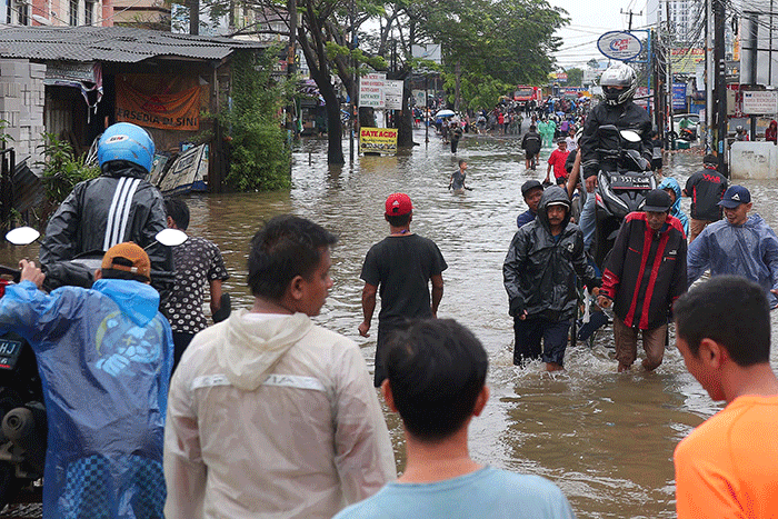 Warga memanfaatkan jasa gerobak untuk melewati banjir di Jalan KH Hasyim Ashari, Kota Tangerang, Banten, Sabtu (16/7/2022).