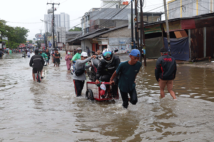 Warga memanfaatkan jasa gerobak untuk melewati banjir di Jalan KH Hasyim Ashari, Kota Tangerang, Banten, Sabtu (16/7/2022).