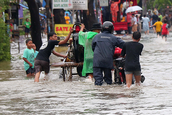 Warga memanfaatkan jasa gerobak untuk melewati banjir di Jalan KH Hasyim Ashari, Kota Tangerang, Banten, Sabtu (16/7/2022).