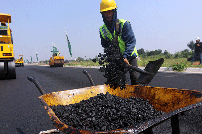 Pekerja menyelesaikan proyek pengaspalan plastik di kawasan BSD City, Tangerang, Banten, Kamis (21/7/2022).
