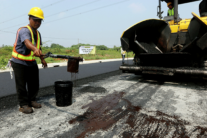 Pekerja menyelesaikan proyek pengaspalan plastik di kawasan BSD City, Tangerang, Banten, Kamis (21/7/2022).