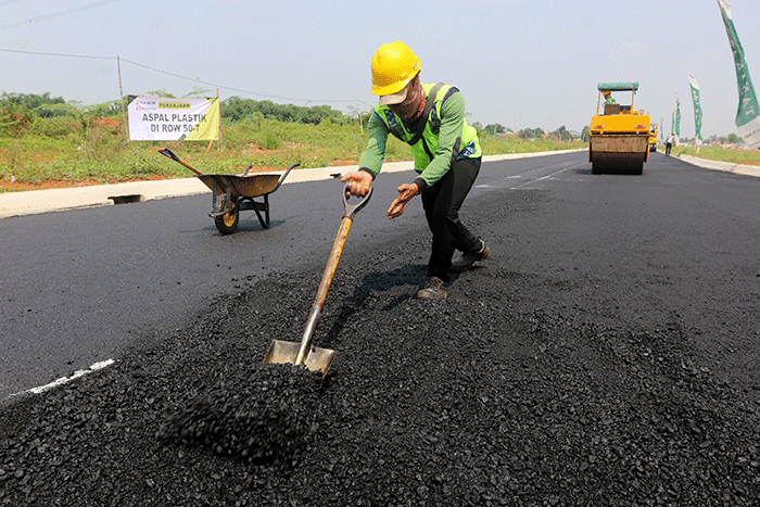 Pekerja menyelesaikan proyek pengaspalan plastik di kawasan BSD City, Tangerang, Banten, Kamis (21/7/2022).