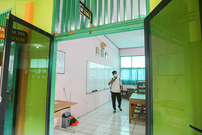 Petugas saat melakukan penyemprotan rutin cairan disinfektan di ruang kelas SMAN 113 Jakarta Timur, Selasa (9/8/2022).