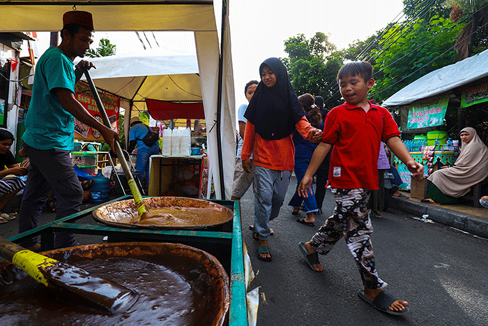 Pengunjung saat mencoba mengaduk dodol Betawi di Festival Rawa Belong, Jakarta Barat, Minggu (14/8/2022).