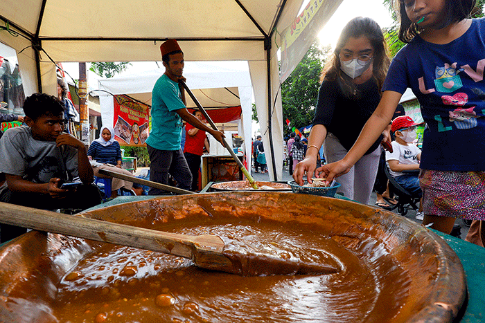 Pengunjung saat mencoba mengaduk dodol Betawi di Festival Rawa Belong, Jakarta Barat, Minggu (14/8/2022).