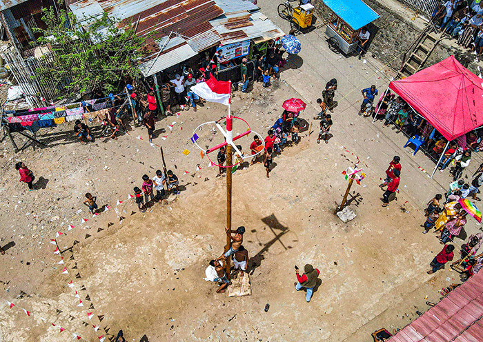 Sejumlah peserta lomba panjat pinang berusaha memanjat untuk meraih amplop berisi uang tunai di Jalan Malengkeri, Makassar, Rabu (17/8/2022).