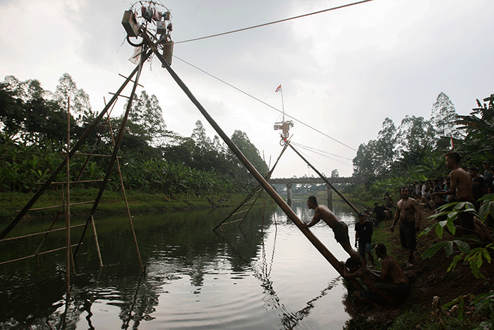 Sejumlah peserta saat berusaha mencapai puncak saat lomba panjat pinang di aliran Banjir Kanal Timur, Duren Sawit, Jakarta Timur, Minggu (21/8/2022).