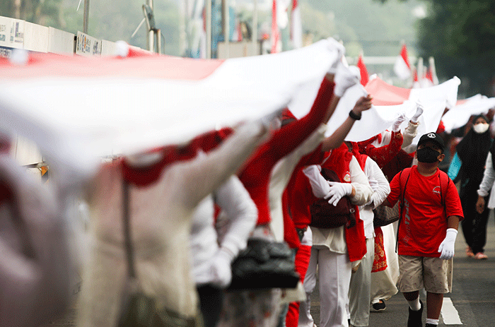 Ratusan warga kompak membawa Bendera Merah Putih sepanjang 1.700 meter di Jakarta, Minggu (28/8/2022).