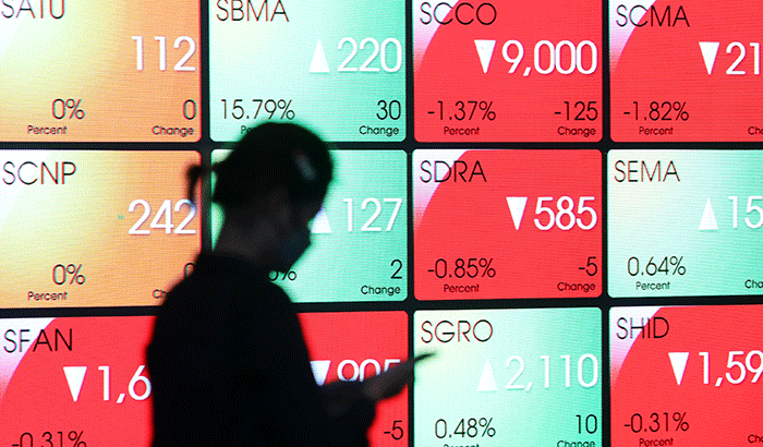 Pekerja melintas di depan layar indeks harga saham gabungan (IHSG) di Gedung Bursa Efek Indonesia, Jakarta, Rabu (7/9/2022).