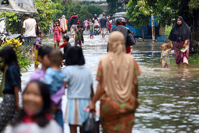 Warga melintasi banjir di permukiman di Kawasan Ciledug Indah, Tangerang, Minggu (11/9/2022).