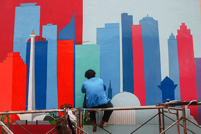 Petugas PPSU membuat mural disalah satu bangunan Kampung Gembira di kawasan Pasar Gembrong, Jakarta Timur, Selasa (13/9/2022).