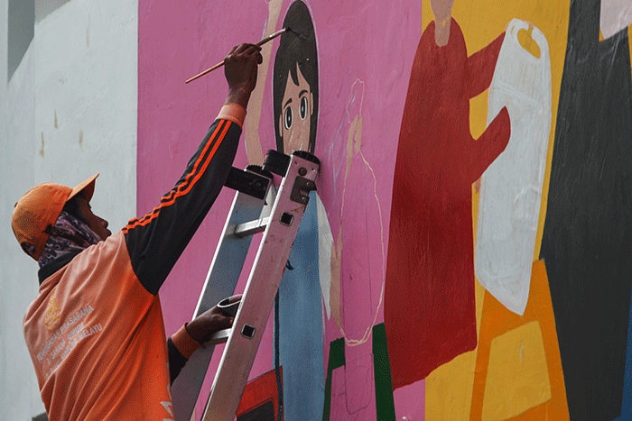 Petugas PPSU membuat mural disalah satu bangunan Kampung Gembira di kawasan Pasar Gembrong, Jakarta Timur, Selasa (13/9/2022).