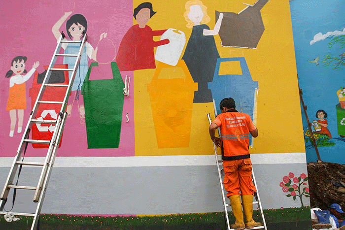 Petugas PPSU membuat mural disalah satu bangunan Kampung Gembira di kawasan Pasar Gembrong, Jakarta Timur, Selasa (13/9/2022).
