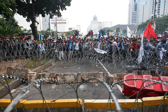Massa aksi menghindar dari kobaran api saat demo menolak kenaikan BBM di kawasan Patung Kuda, Monas, Jakarta Selasa (13/9/2022).